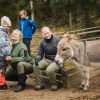 Iloisesti hymyilevä perhe miniaasin seurassa