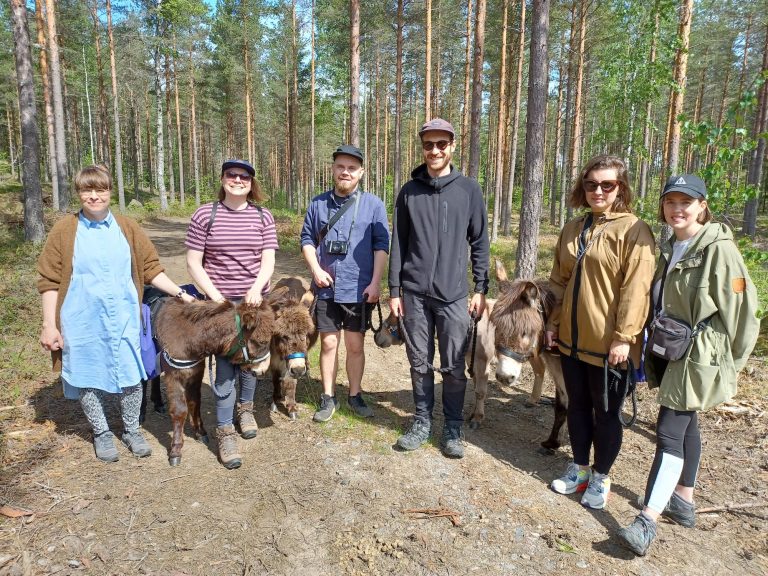 Iloisia ihmisiä metsäretkellä aasien kanssa